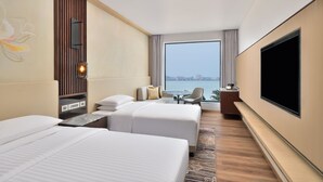 A hotel room with two beds, a TV, a desk with a chair, and a view of the city through large windows. - Courtyard by Marriott Gorakhpur (Gorakhpur)