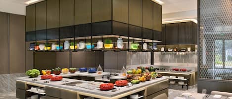 A modern kitchen with a central island, built-in appliances, and a variety of colorful plants.