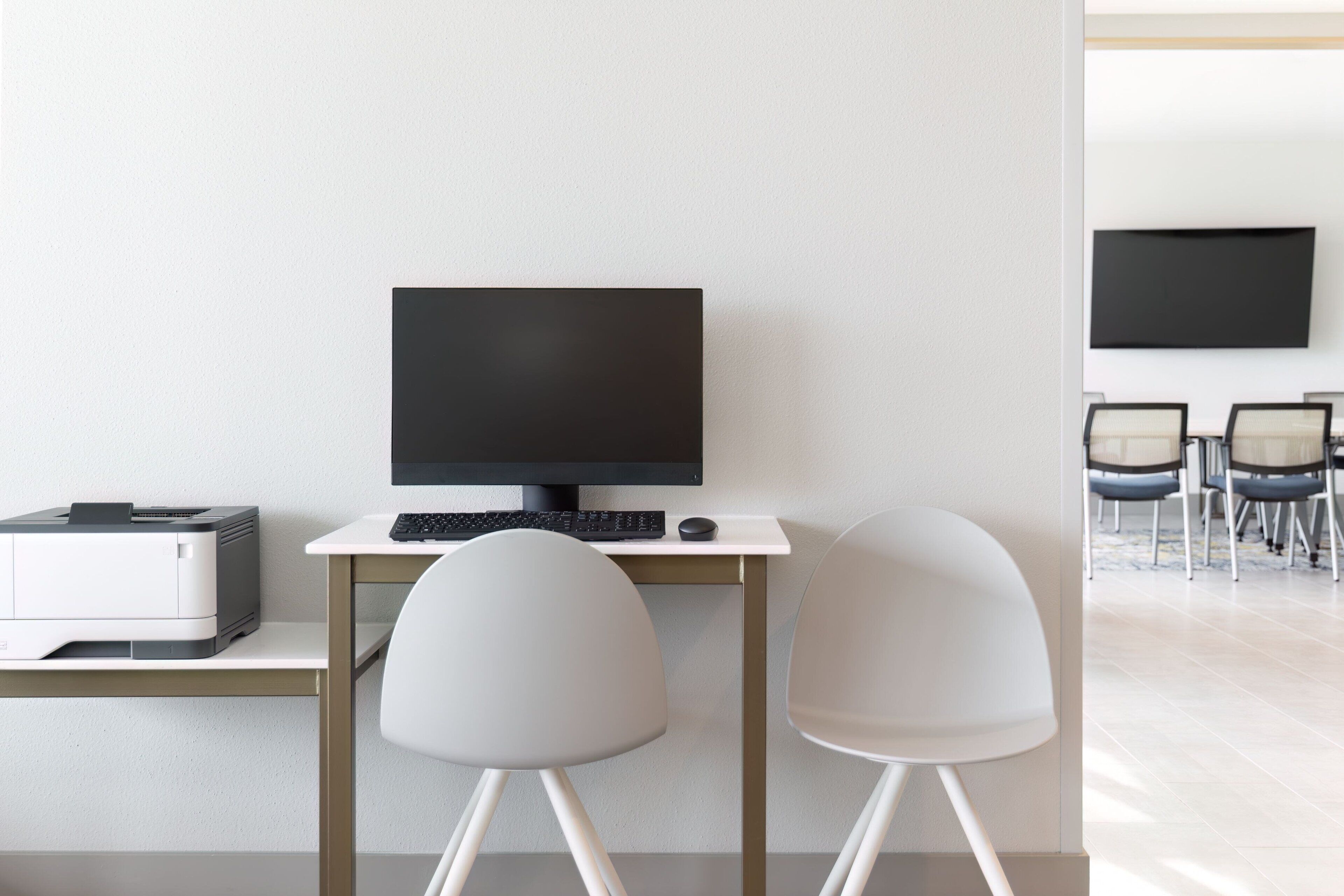 Un bureau moderne équipé d’un ordinateur de bureau, d’une imprimante et de deux chaises.