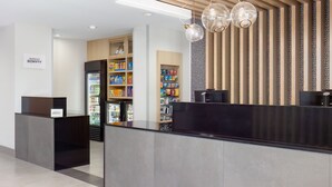 A modern hotel reception area with a black reception desk, a minibar, and a self-service beverage station. - TownePlace Suites by Marriott Pleasanton (Pleasanton)