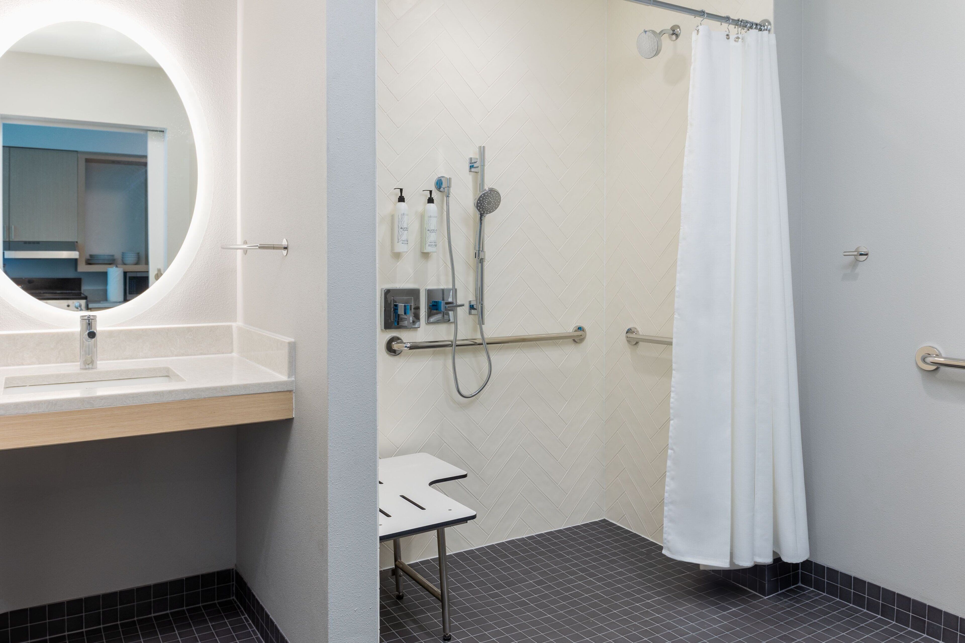 A bathroom with a sink, mirror, shower, and a white curtain.