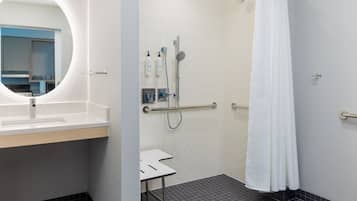A bathroom with a sink, mirror, shower, and a white curtain.