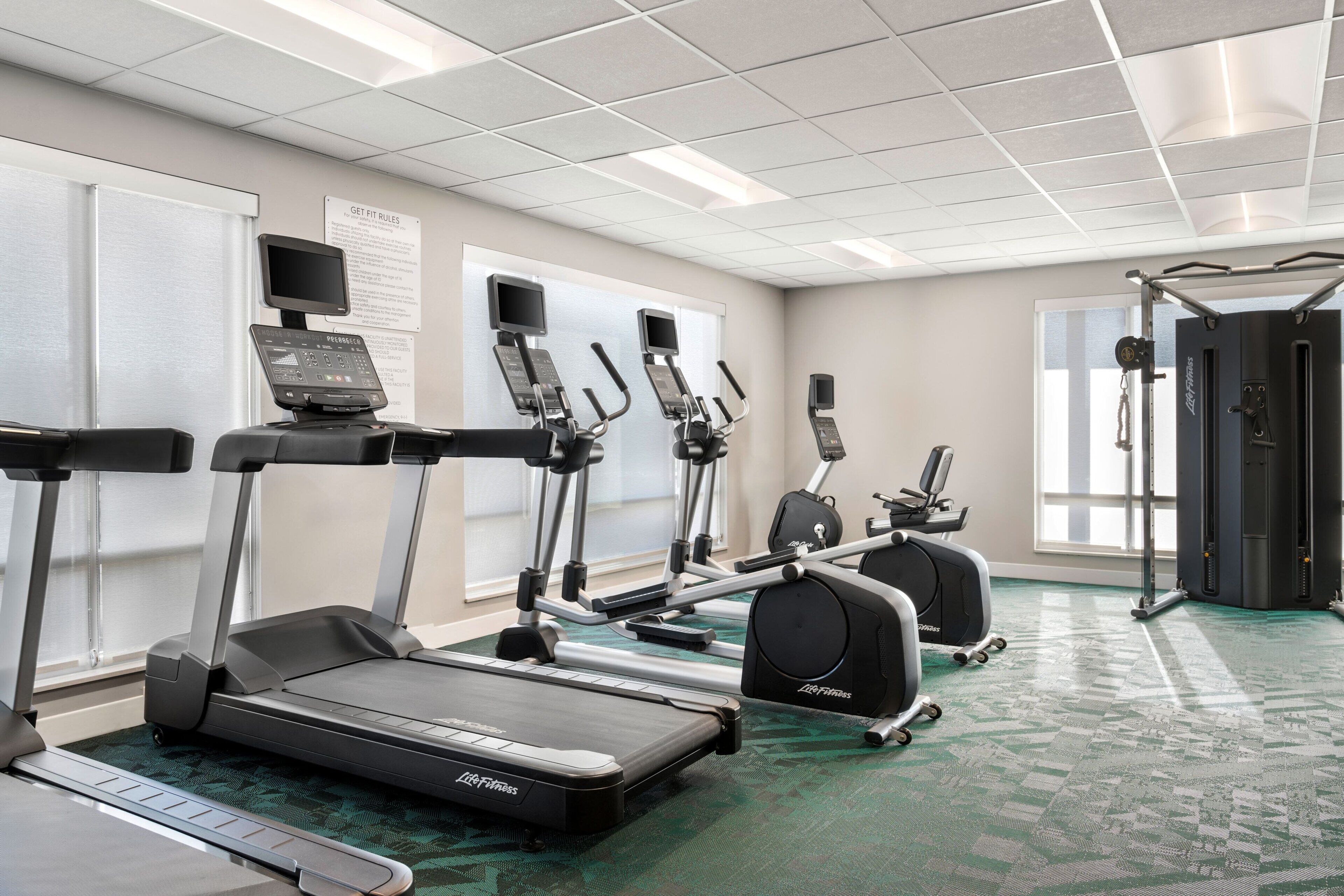 Ein Fitnessstudio mit Laufbändern, Crosstrainern und Gewichten.