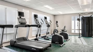Ein Fitnessstudio mit Laufbändern, Crosstrainern und Gewichten.