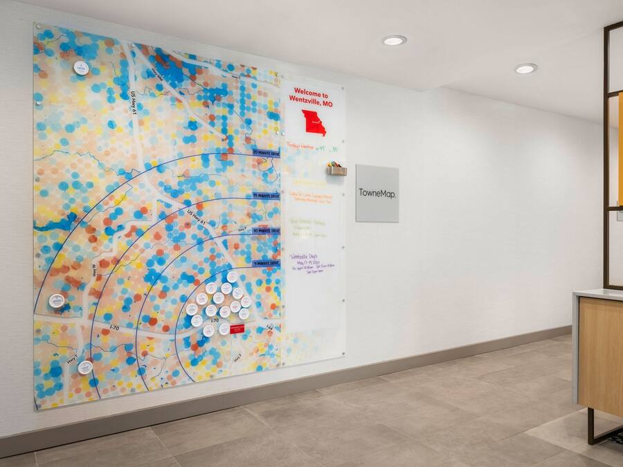 Un couloir orné d’une grande carte colorée au mur, d’une pancarte indiquant « Bienvenue à Wentzville, dans le Missouri », et d’une armoire avec un miroir.