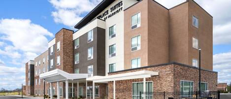 A modern hotel building with a brick facade, multiple windows, and a covered entrance area.