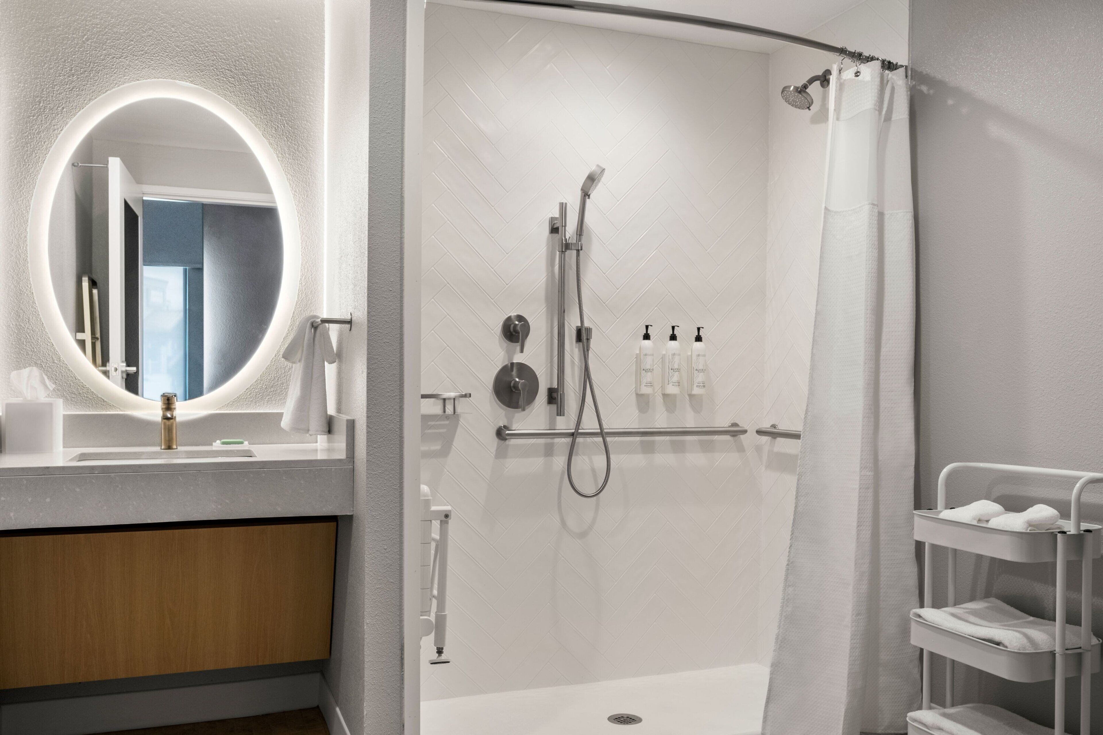 Un baño moderno con ducha, lavabo con espejo y un perchero para toallas.