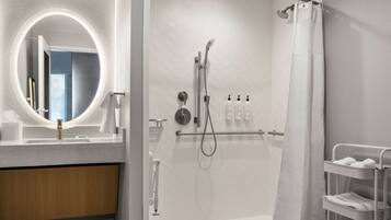 Un baño moderno con ducha, lavabo con espejo y un perchero para toallas.