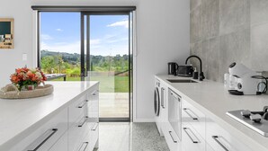 Cozinha moderna com uma janela ampla, máquina de lavar e cafeteira.