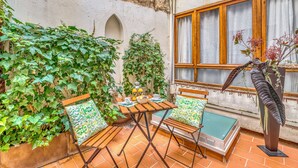 Eine Terrasse mit Tisch und Stühlen, umgeben von üppiger Bepflanzung und einer Zierpflanze.