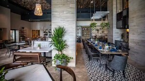 A spacious restaurant with high ceilings, exposed beams, and a mix of seating arrangements including tables and booths. - Resort Condo at Wyndham Grand Rio Mar (Río Grande)