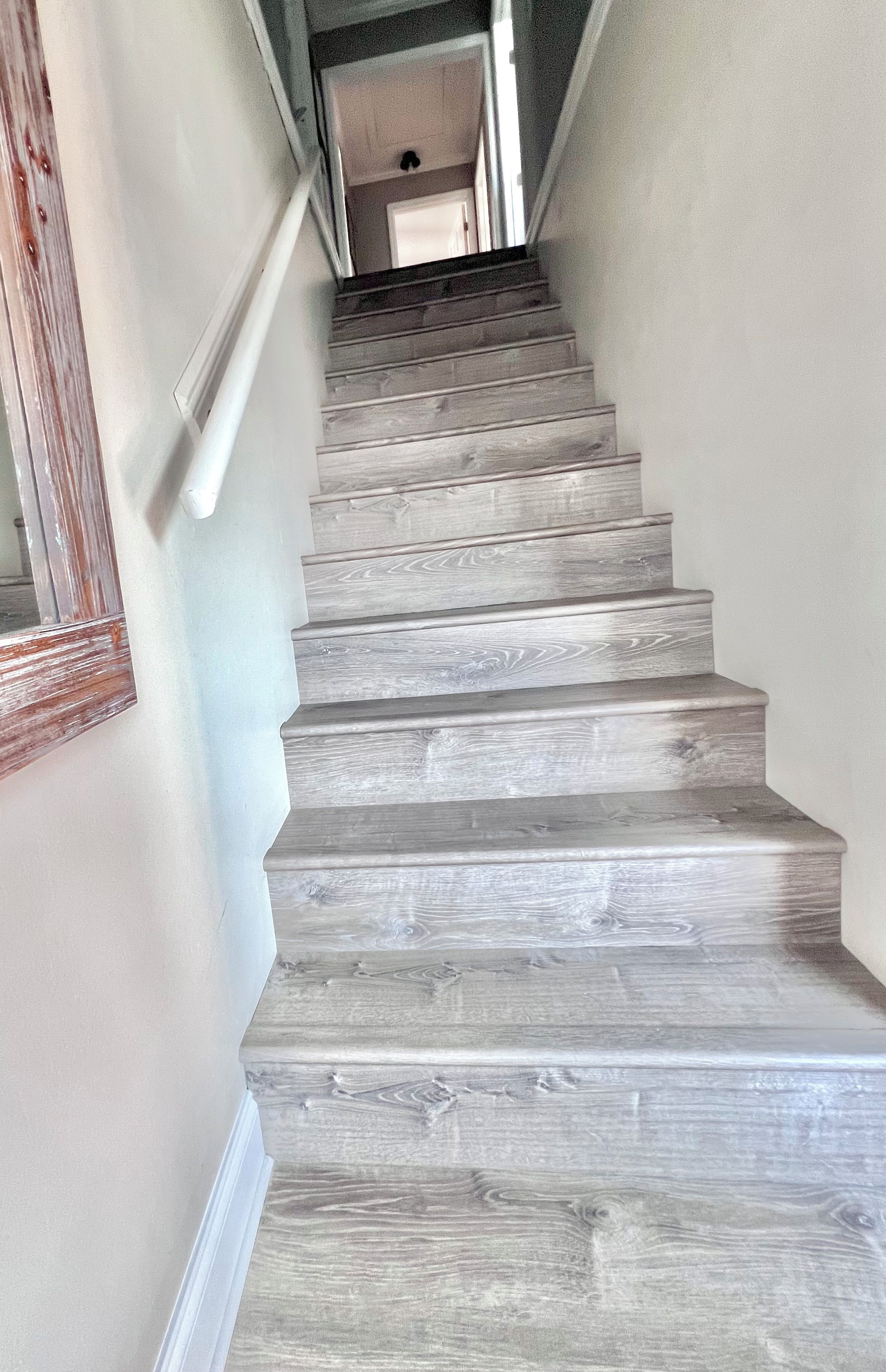 A staircase with a gray wooden finish, leading to an upper floor.