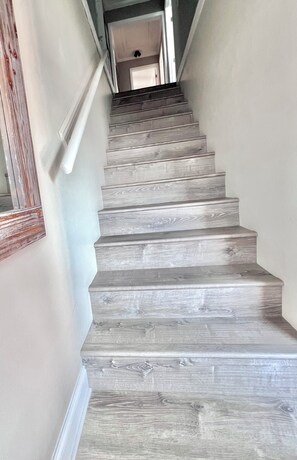 Un escalier avec des marches en bois gris, menant à l’étage supérieur.