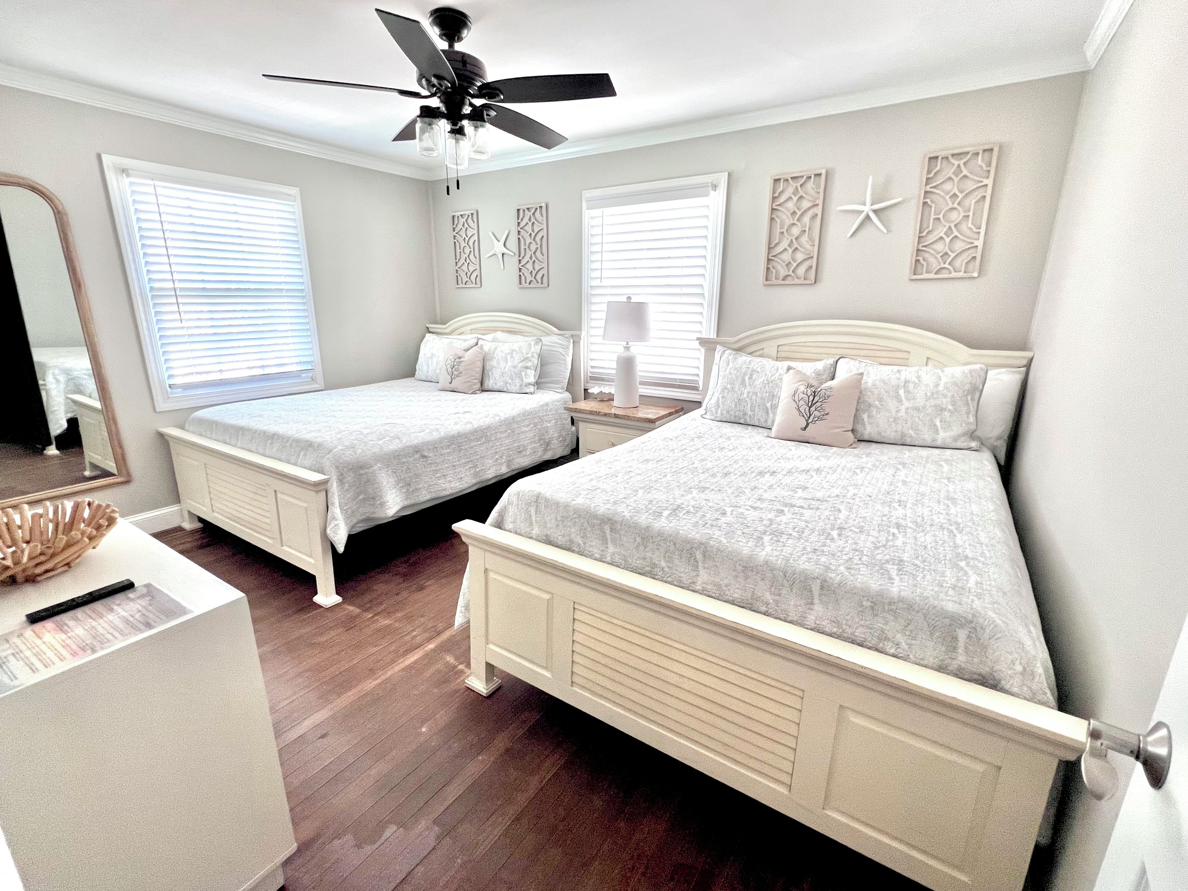 A bedroom with two single beds, a ceiling fan, and decorative wall art.