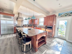 A spacious kitchen with a large island, stainless steel appliances, and wooden cabinetry. - NEW! The Oasis on Primo! Next To Margaritaville & In The Heart of Time Square! (Fort Myers Beach)