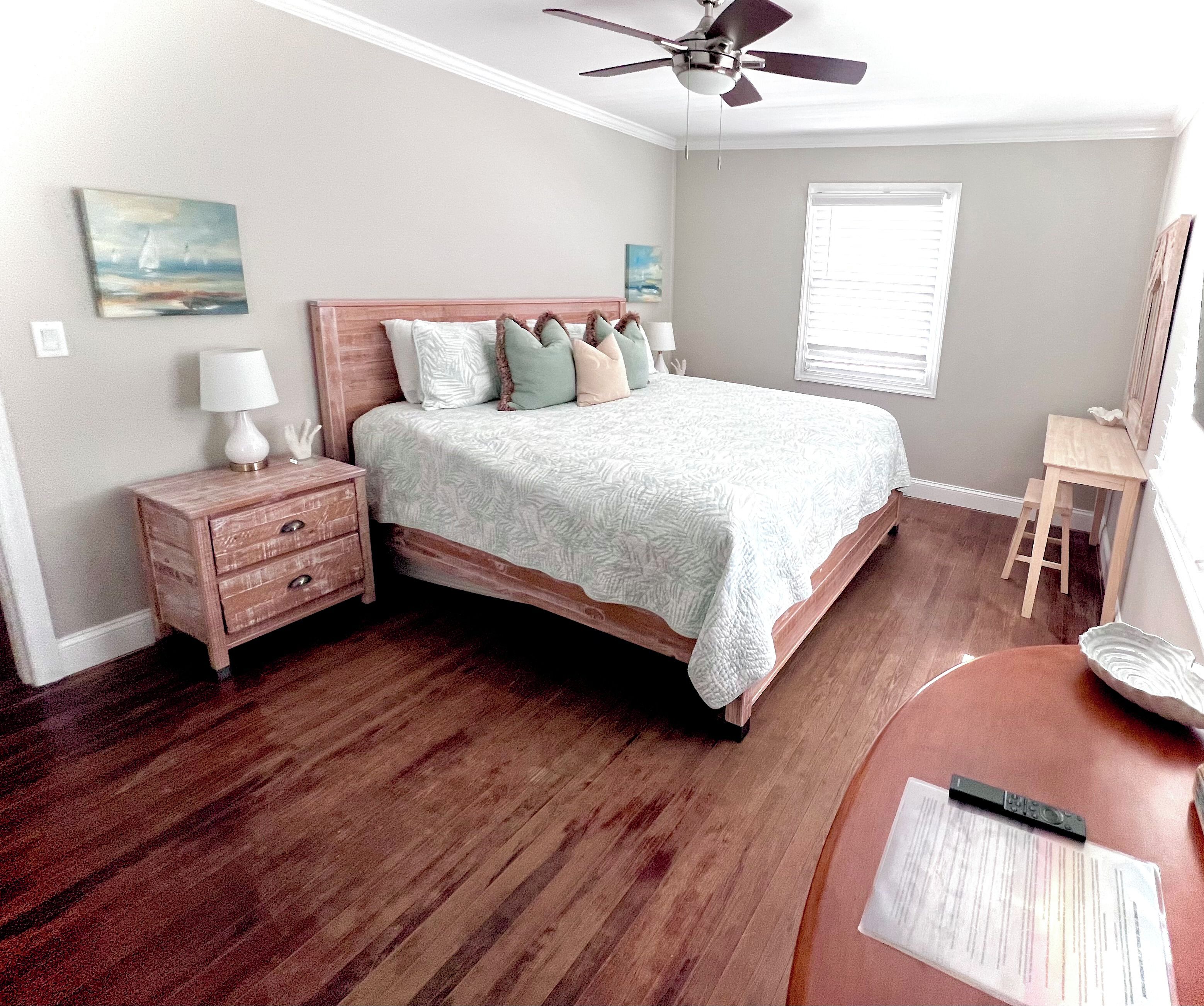 A bedroom with a bed, nightstand, lamp, and a ceiling fan.