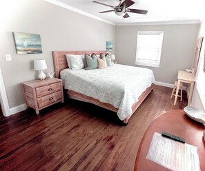 A bedroom with a bed, nightstand, lamp, and a ceiling fan.