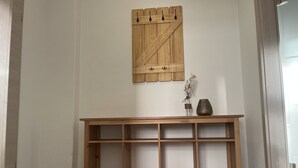 Ein Holzkonsolentisch mit mehreren Ablagen, eine dekorative Holzvertäfelung darüber und eine Vase mit Blumen auf der rechten Seite.