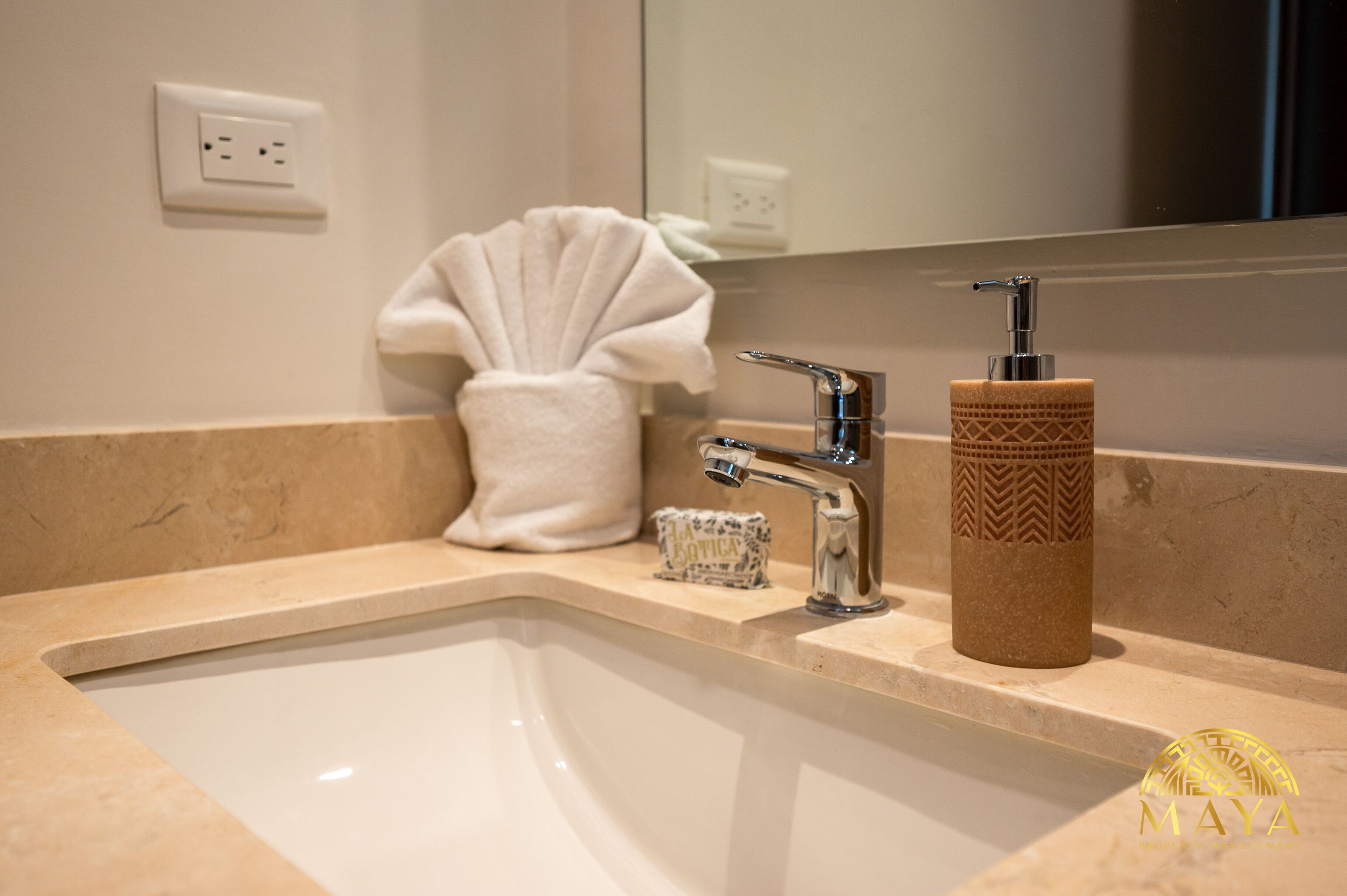 A bathroom sink with a mirror, a towel, and a soap dispenser.