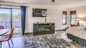Un dormitorio con una cama grande, un ventilador de techo, un televisor y vistas al exterior.