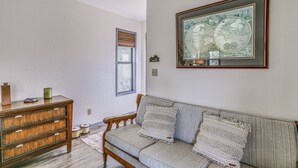 Un salón con un aparador de madera, un sofá gris con cojines estampados y un mapa mundial enmarcado en la pared.