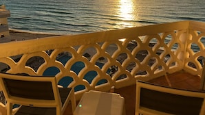 En balkon med udsigt over havet i solnedgang.