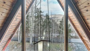 A room with a large window featuring a wooden frame and a hanging light fixture. - Walk to Ski Lift! Charming Hunter A-Frame (Lanesville)