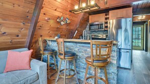 A cozy cabin-style kitchen with wooden walls, a stone backsplash, and a stainless steel refrigerator. - Walk to Ski Lift! Charming Hunter A-Frame (Lanesville)