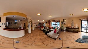 Un vestíbulo de hotel con mostrador de recepción, zona de estar y detalles decorativos.