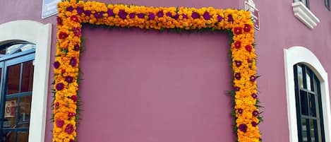 Entrada de hotel con un arco de flores de cempasúchil y un letrero que dice 'HOTEL SAN JOSE'.
