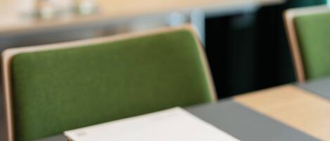 A table with a green chair, a white notepad, a pen, and an apple.