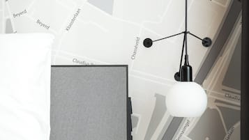 Ett modernt hotellrum med en vägg dekorerad med en karta, en säng, ett sängbord och en hängande lampa.
