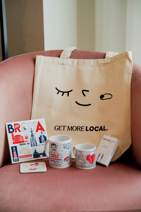 A brown tote bag with a smiling face and the text "GET MORE LOCAL." on a pink chair.