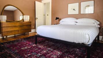 A bedroom with a bed, a dresser, a mirror, and a door.