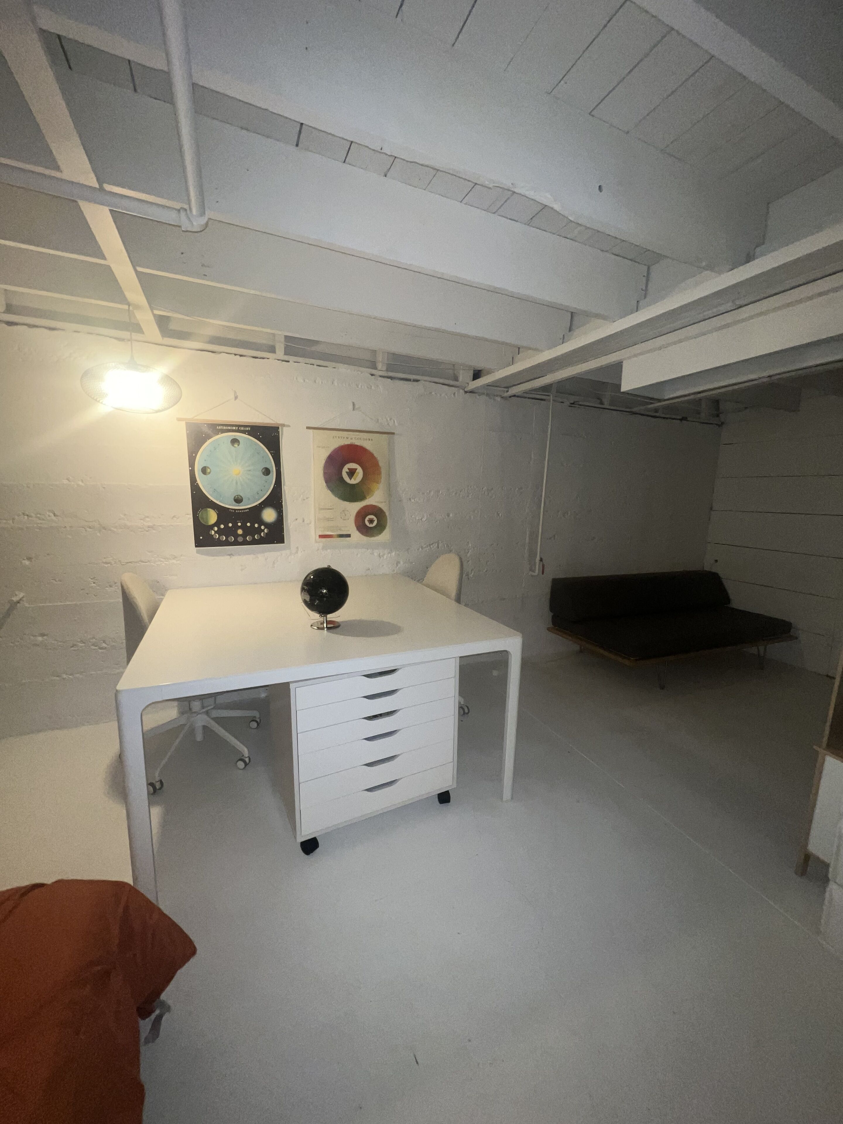 A room with a white desk, a globe, and two posters on the wall.