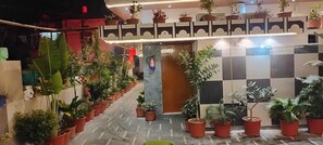 A hotel corridor with potted plants lining the walls and a checkered floor pattern. - ANAND LOK VARANASI  (Varanasi)