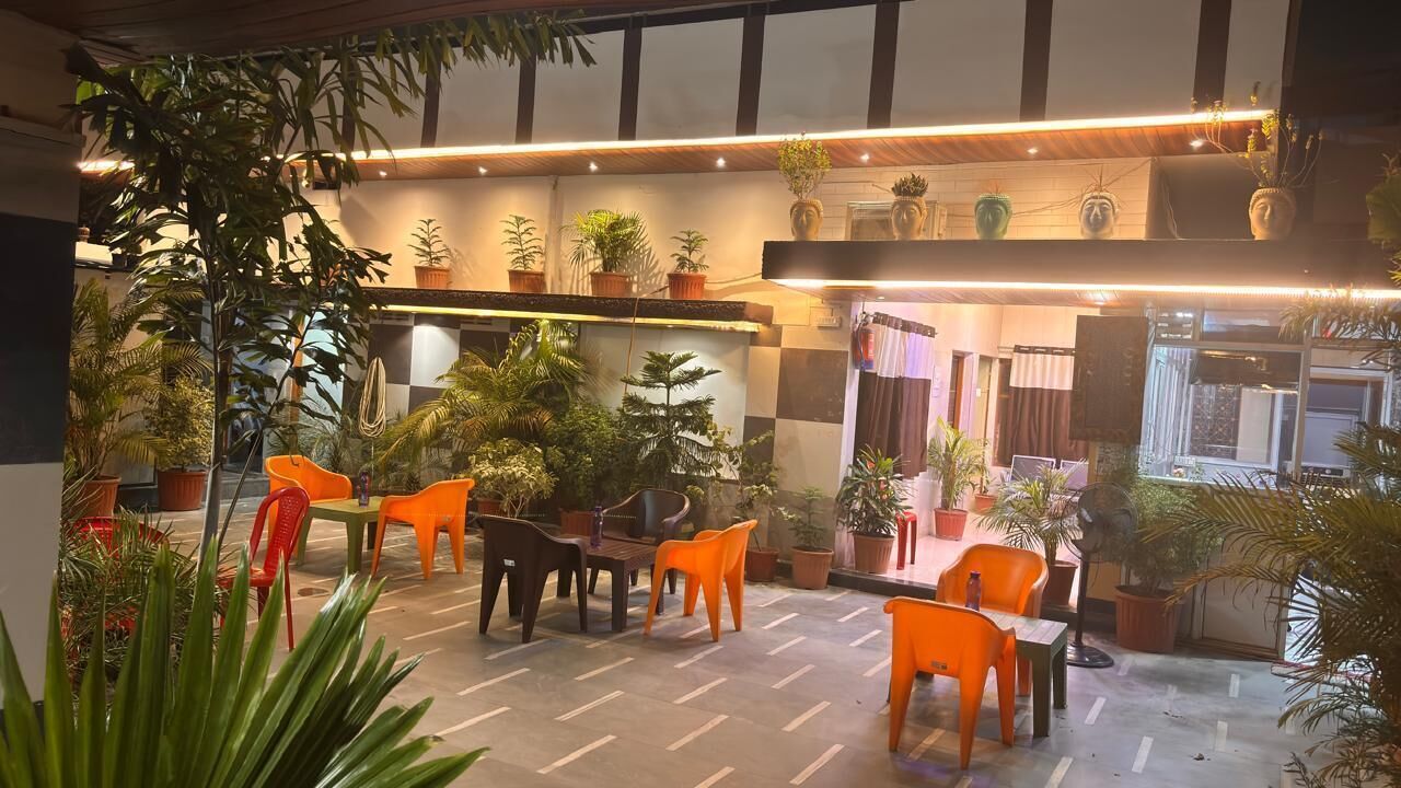 An indoor seating area with tables and chairs, surrounded by potted plants.