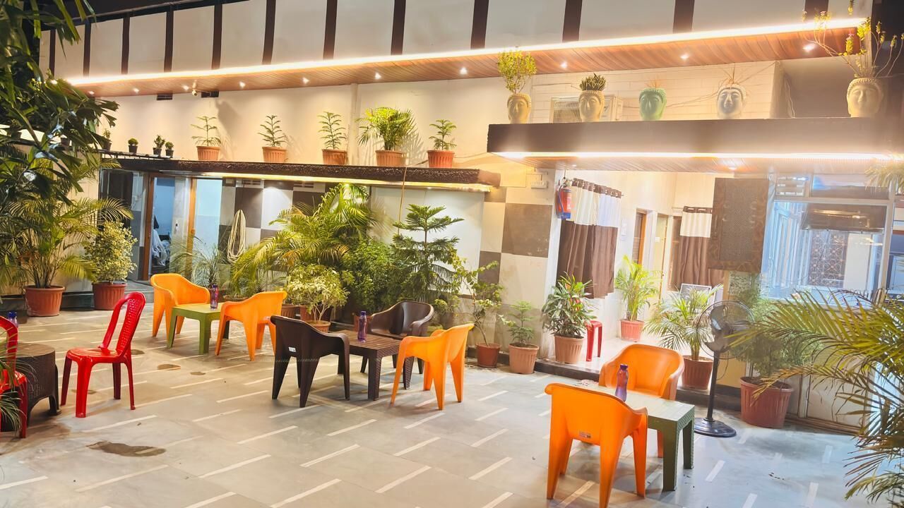 A hotel lobby with multiple seating areas, potted plants, and a checkered floor pattern.