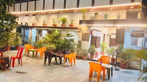 A hotel lobby with multiple seating areas, potted plants, and a checkered floor pattern. - ANAND LOK VARANASI  (Varanasi)