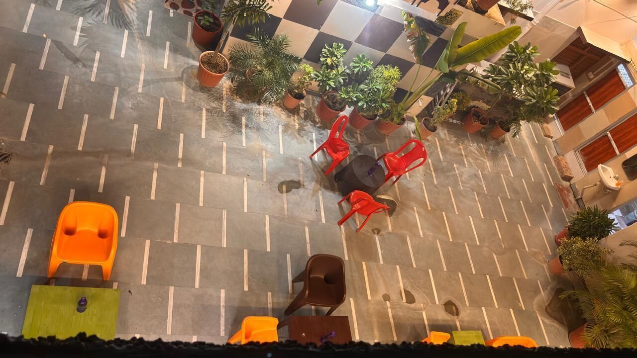 A courtyard with potted plants, a checkered floor, and outdoor seating.