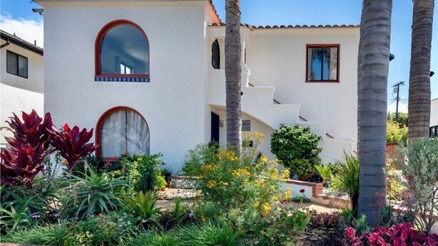 A two-story building with a white exterior and red-tiled roof. There are two visible windows, one with a red frame and another with a white frame. The building has a small porch area with a brick border. - Fully Renovated 2 BR House by Palos Verdes, Beach, in Quiet Neighborhood (Los Angeles)