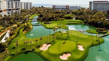 A golf course with bunkers, water hazards, and palm trees.