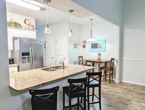A modern kitchen with a granite countertop, stainless steel appliances, and pendant lighting. - BEACH~HEATED POOL~PET FRIENDLY-WINTER STAY (Corpus Christi)