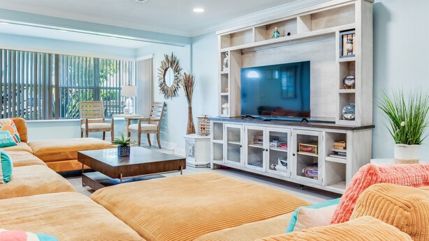 Ein Wohnzimmer mit einem großen Fernseher, Holzmöbeln und einem Bücherregal.