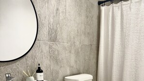 A bathroom with a white sink, mirror, toilet, and shower curtain. - SouthWest Private Cozy Studio (Miami)