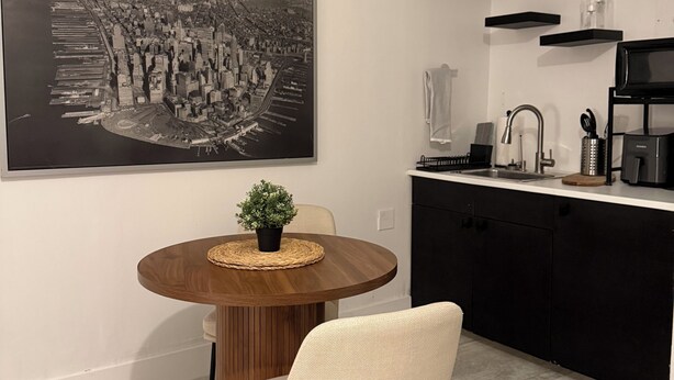 A modern kitchen with a black countertop, a built-in microwave, and a coffee maker. - SouthWest Private Cozy Studio (Miami)