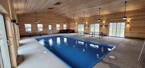 Una piscina interior con paredes y techo de madera, bancos e ventiladores de techo.