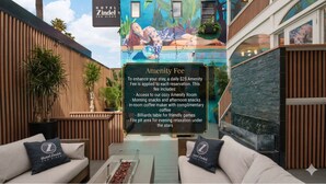 Un hall d’hôtel orné d’une fresque murale, un panneau indiquant le montant des frais de service et un espace détente avec un foyer.