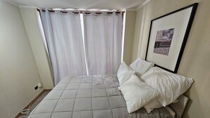 A bedroom with a large bed, white curtains, and a framed picture on the wall. - Dardigniac (Santiago)