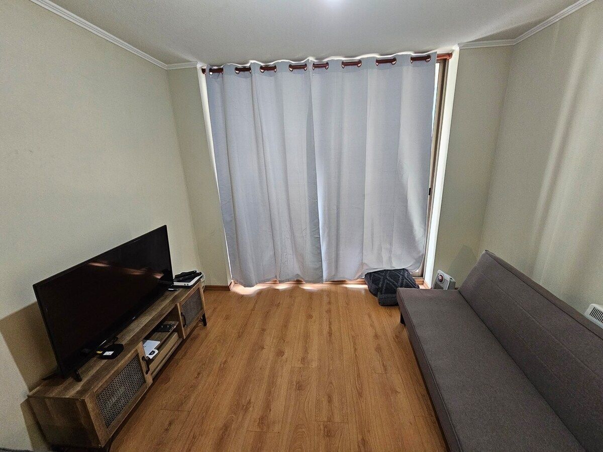 Un salon équipé d’un téléviseur à écran plat, d’un canapé et d’un parquet.